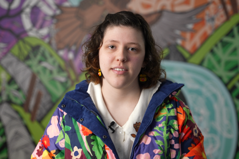 Willow, a disabled young person wearing a colourful jacket, looking at the camera.